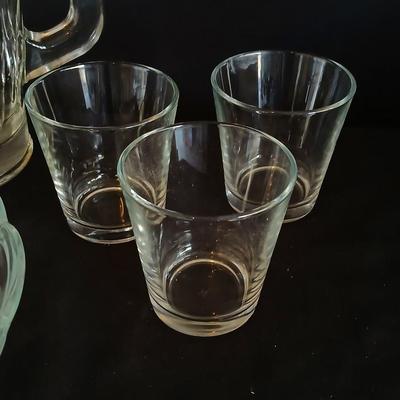 Glass water pitcher with six small juice glasses and a snack bowl with a platter