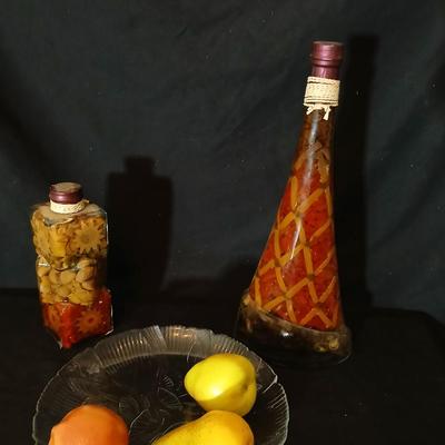 Two decorative garnish bottles with a glass plate and faux fruit