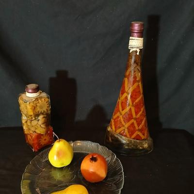 Two decorative garnish bottles with a glass plate and faux fruit
