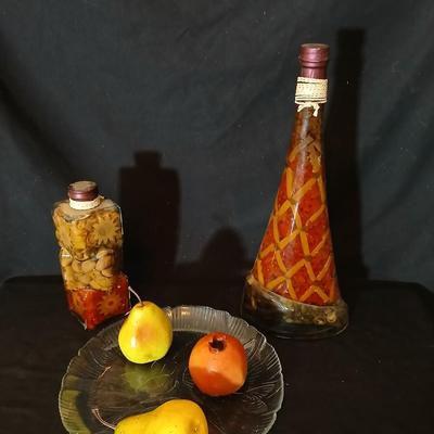 Two decorative garnish bottles with a glass plate and faux fruit