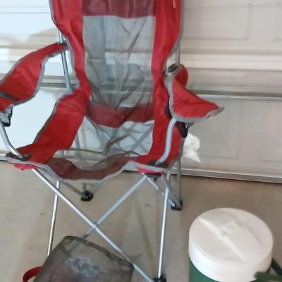 Mesh folding camp chair with carry bag and a green igloo drink cooler