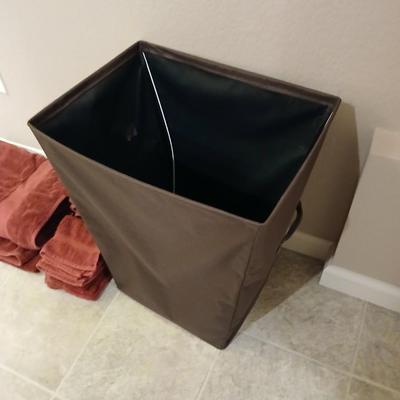 Brown laundry hamper with assortment of reddish /maroon towels