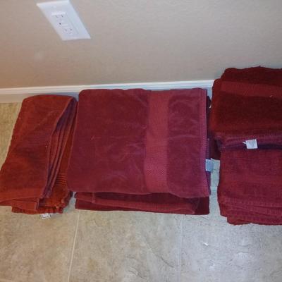 Brown laundry hamper with assortment of reddish /maroon towels