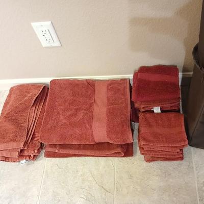 Brown laundry hamper with assortment of reddish /maroon towels
