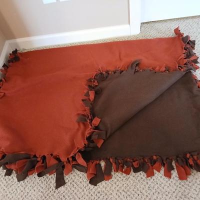Two throw pillows and a handmade knot lap blanket