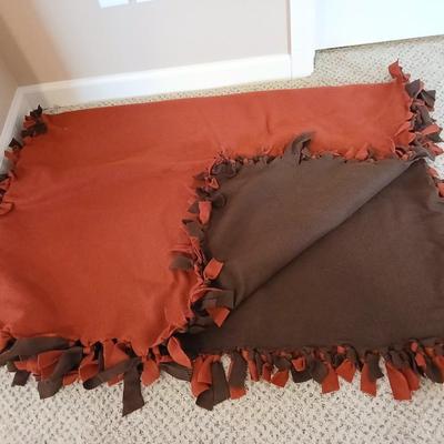 Two throw pillows and a handmade knot lap blanket