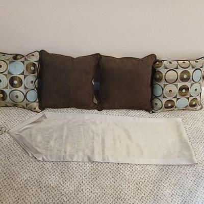 Four throw pillows and a long grey table runner