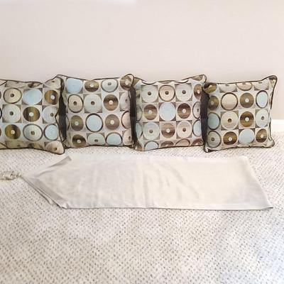 Four throw pillows and a long grey table runner