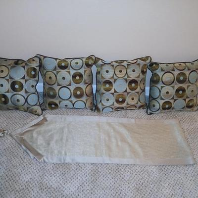 Four throw pillows and a long grey table runner