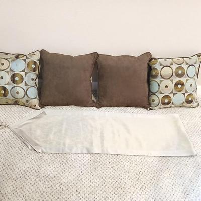Four throw pillows and a long grey table runner