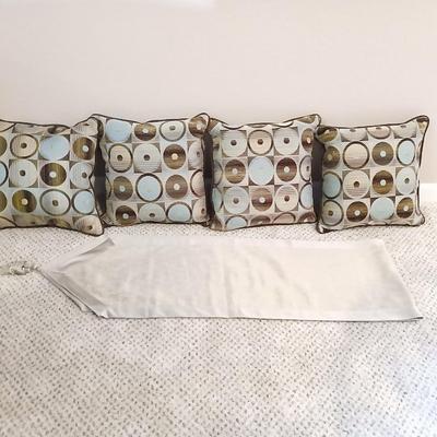 Four throw pillows and a long grey table runner