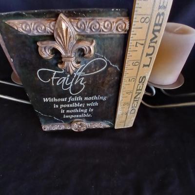 Two metal candle sconces with two candles and two decorative balls and a religious plaque
