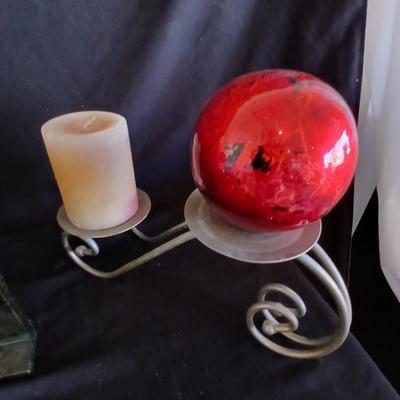 Two metal candle sconces with two candles and two decorative balls and a religious plaque