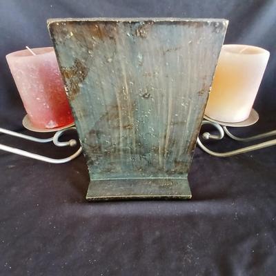 Two metal candle sconces with two candles and two decorative balls and a religious plaque