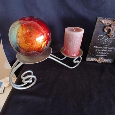 Two metal candle sconces with two candles and two decorative balls and a religious plaque
