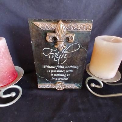 Two metal candle sconces with two candles and two decorative balls and a religious plaque
