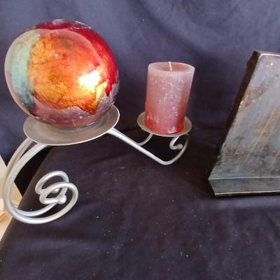 Two metal candle sconces with two candles and two decorative balls and a religious plaque