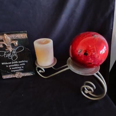 Two metal candle sconces with two candles and two decorative balls and a religious plaque