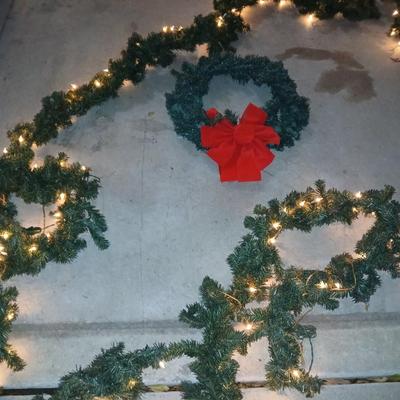 Pre-lit pine garland and a wreath with a red bow