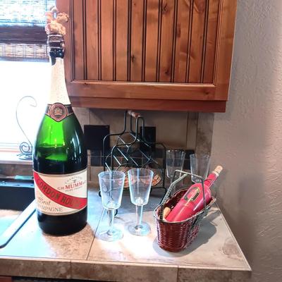 TALL EMPTY CHAMPAGNE BOTTLE, WINE RACK, BOTTLE HOLDER AND 4 STEMMED GLASSES