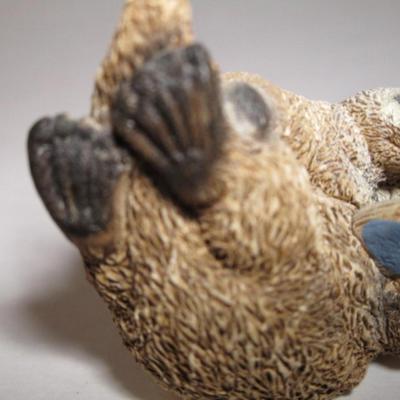 Sea otter reading a book to its child figurine