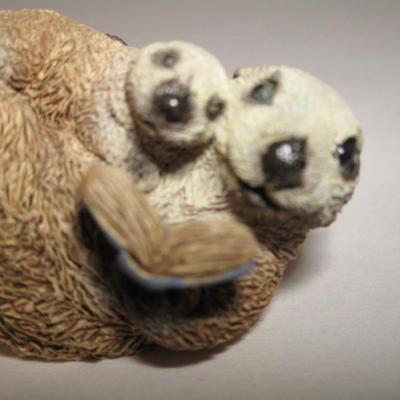Sea otter reading a book to its child figurine