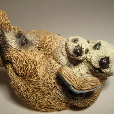 Sea otter reading a book to its child figurine