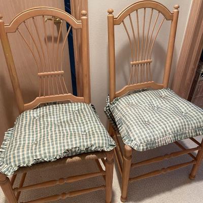 Two lightwood chairs with wicker bases