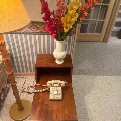 Small multi level table fake flowers in white pot and rotary phone