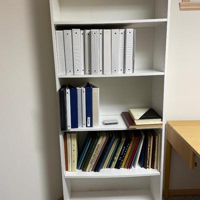 White bookshelf with binders and vintage yearbooks
