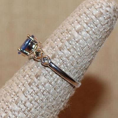 Size 7 Oval Blue 4 Prong Main Stone Ring with "Looped" Side Accents on a Silver Tone Band (2.2g)