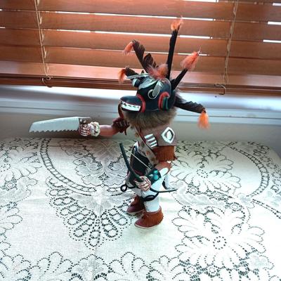 KACHINA DOLL HAND CARVED & PAINTED W/FUR & FEATHERS WIELDING A HAND SAW