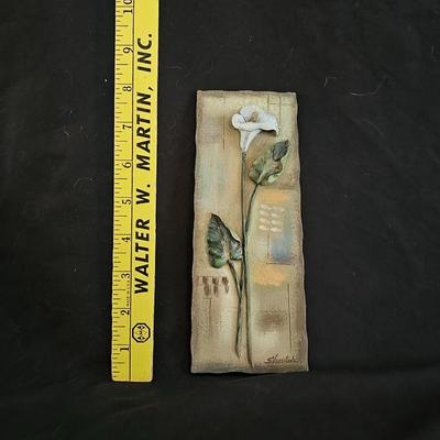 Faux cala lilies in a vase with four floral wall hanging plaques