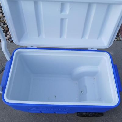 Folding camping chair with clean Igloo cooler on wheels