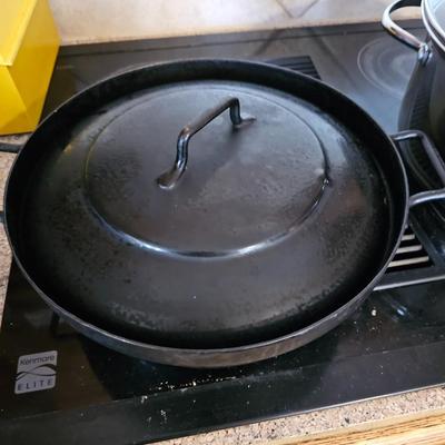 Large stew pot with lid, smaller pot with lid, utensils, and cookbooks