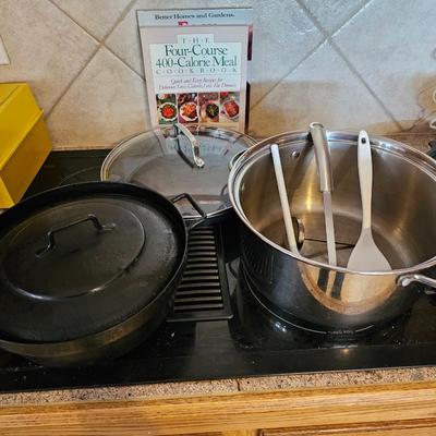 Large stew pot with lid, smaller pot with lid, utensils, and cookbooks