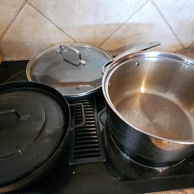 Large stew pot with lid, smaller pot with lid, utensils, and cookbooks