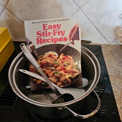 Large stew pot with lid, smaller pot with lid, utensils, and cookbooks