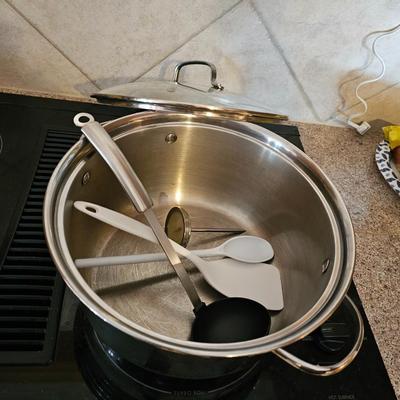 Large stew pot with lid, smaller pot with lid, utensils, and cookbooks