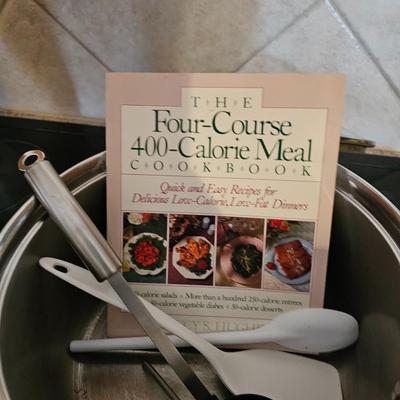 Large stew pot with lid, smaller pot with lid, utensils, and cookbooks