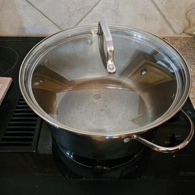 Large stew pot with lid, smaller pot with lid, utensils, and cookbooks