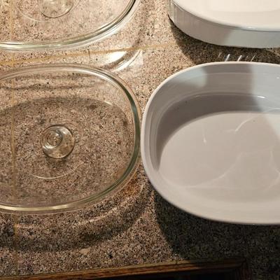 Two corning casserole dishes with lids and a Corning counter cutting board
