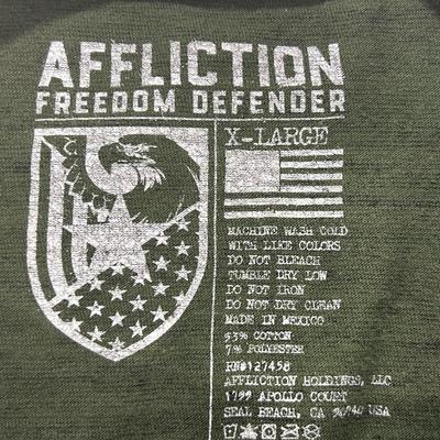 Sale Photo Thumbnail #406: Affliction Freedom Defender Men’s XL T-Shirt. Please note the hole (located on back/bottom/middle) as depicted in last photo. Additionally, there are four pin sized holes scattered throughout.