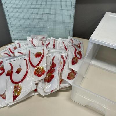 Multiple sets of red fashion jewelry in a small storage container