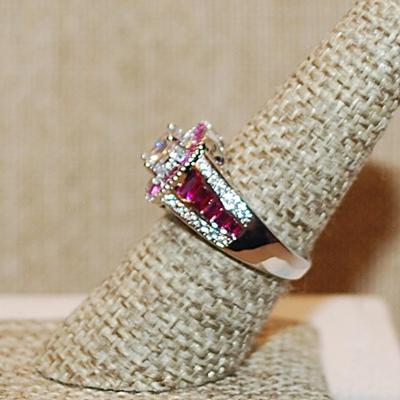 Size 7 ½ RUBY RED Border & Accents Surrounding a Clear Round Stone Ring on a Silver Tone Band (5.6g)