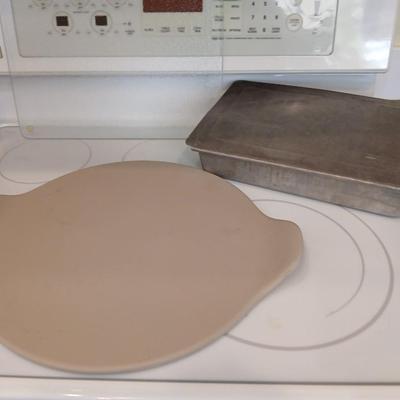Pampered Chef 15 inch handled pizza stone with glass cutting board and a lidded metal cake pan