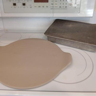 Pampered Chef 15 inch handled pizza stone with glass cutting board and a lidded metal cake pan