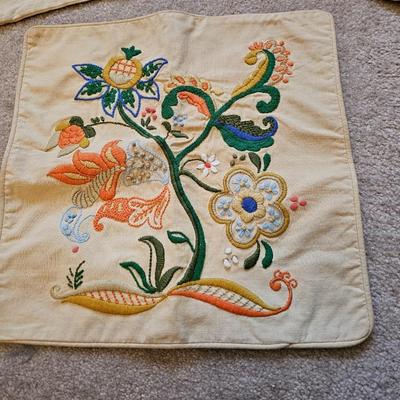 Four Vintage Crewel Embroidery Pillowcases with a variety of wicker baskets and a framed floral embroidered wall art