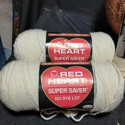 8 skeins of Red Heart Super saver yarn with a basket and knitting needles