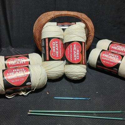 8 skeins of Red Heart Super saver yarn with a basket and knitting needles